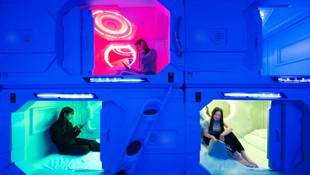 A futuristic room with a central glowing structure, individual seating areas, and a control panel. - HB INN (Hiroshima)