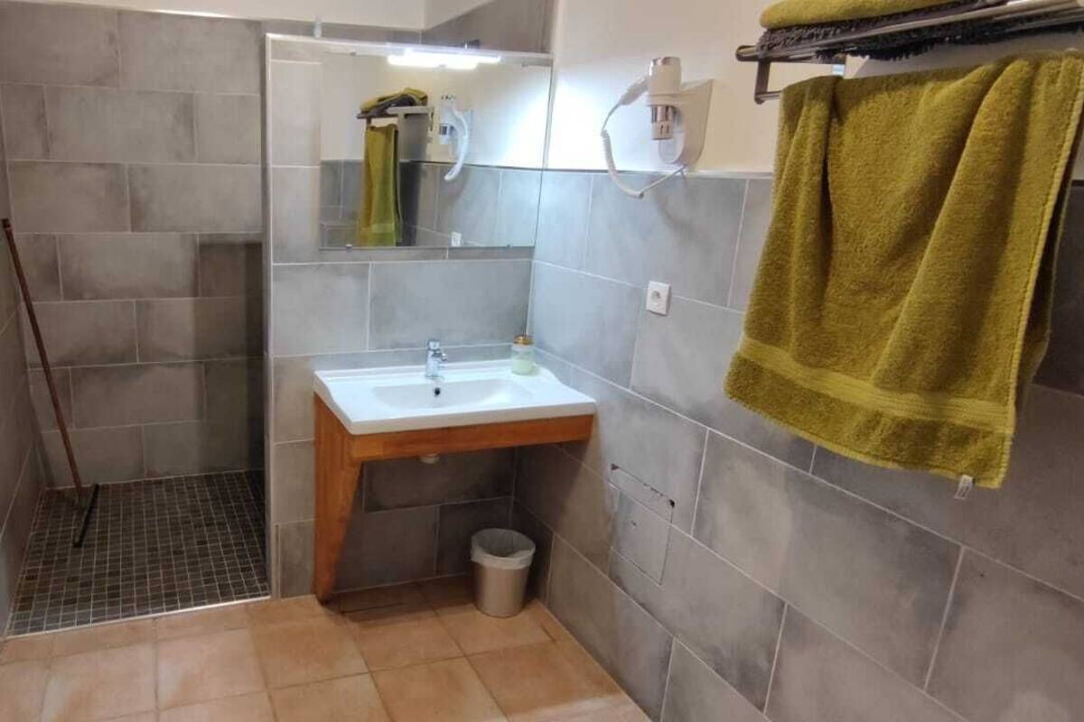Une salle de bain avec une douche, un lavabo et un porte-serviettes.