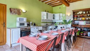 Une cuisine équipée d’une table à manger pour six personnes, de meubles blancs, d’un four à micro-ondes et d’une variété d’ustensiles de cuisine.