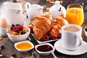 Een ontbijt met croissants, bessen, ontbijtgranen, koffie en sap.
