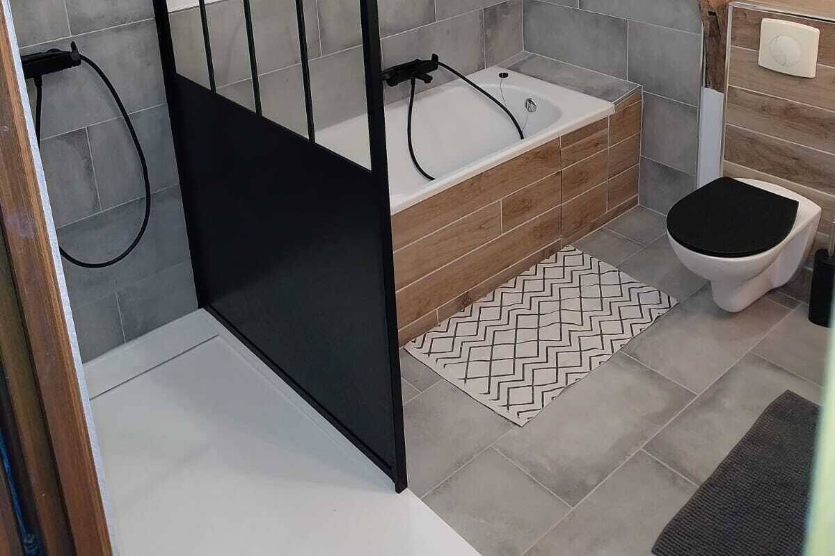 Une salle de bain moderne avec une douche, une baignoire, des toilettes et un tapis à motifs en chevrons.