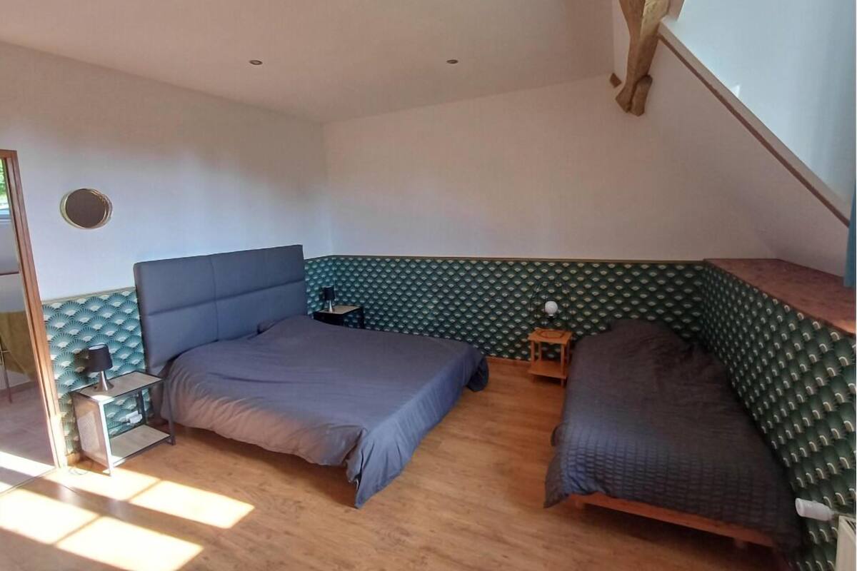 Une chambre avec deux lits, une petite table de chevet, un miroir et une fenêtre avec une poutre en bois.