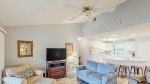 Ein modernes Wohnzimmer mit Flachbildfernseher, zwei Sofas, einem Couchtisch und Deckenventilator.