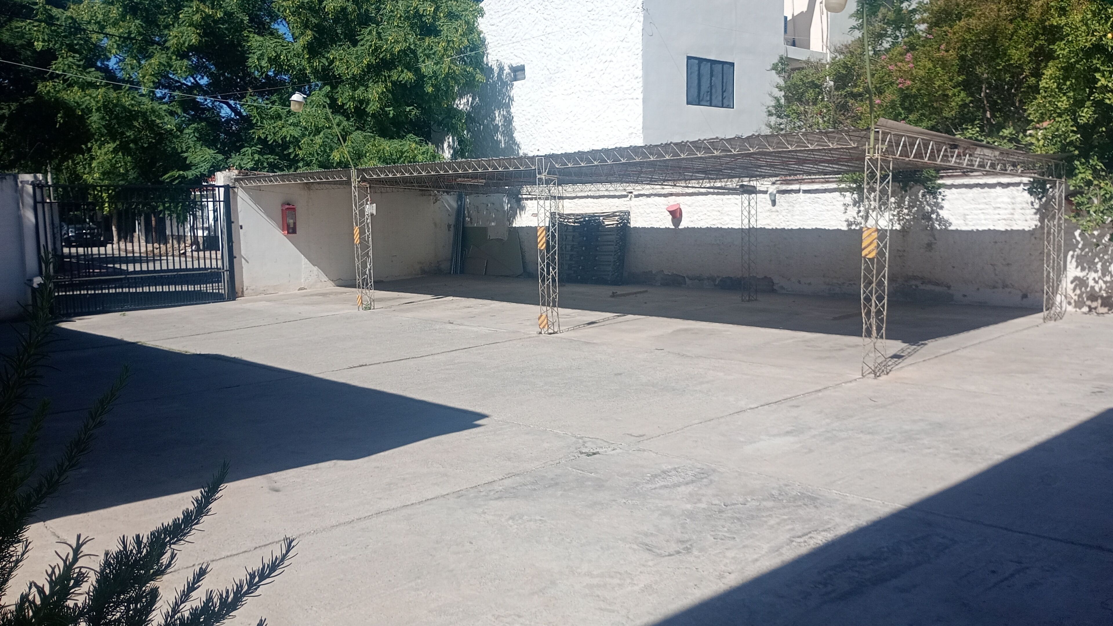 A covered outdoor area with a concrete floor, metal railings, and a gated entrance.