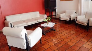A living room with a sofa, two armchairs, a coffee table with a plant, a television, and a painting on the wall. - Hotel Asembal (Cafayate)