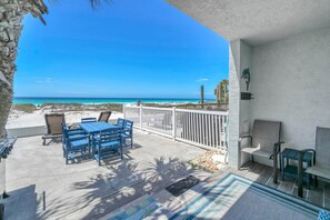 Une terrasse avec des meubles d’extérieur, une vue sur la plage et une fresque représentant des dauphins sur le mur.