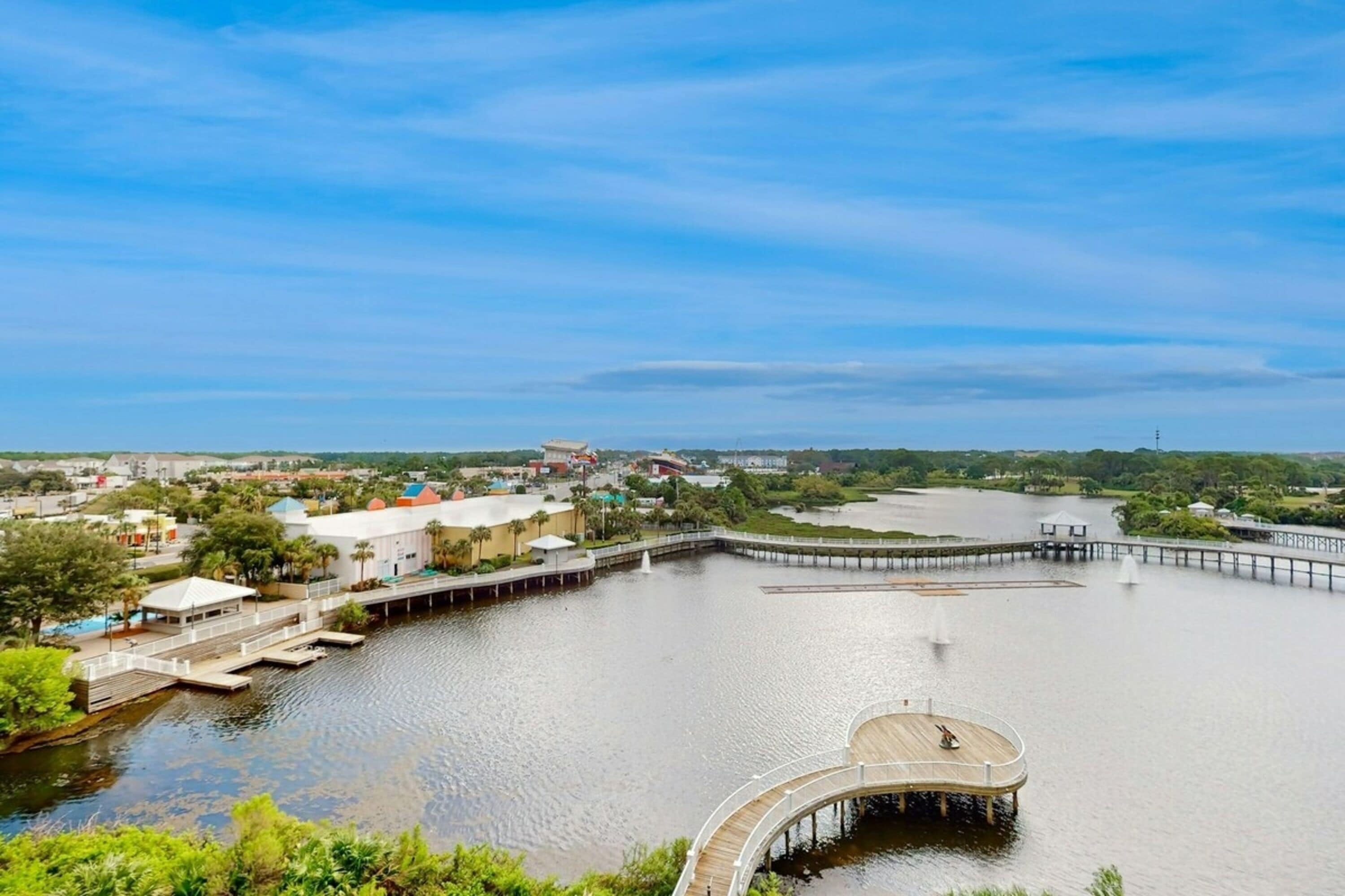 Una zona ribereña con un muelle, un pabellón y un puente que conecta con tierra firme distante.