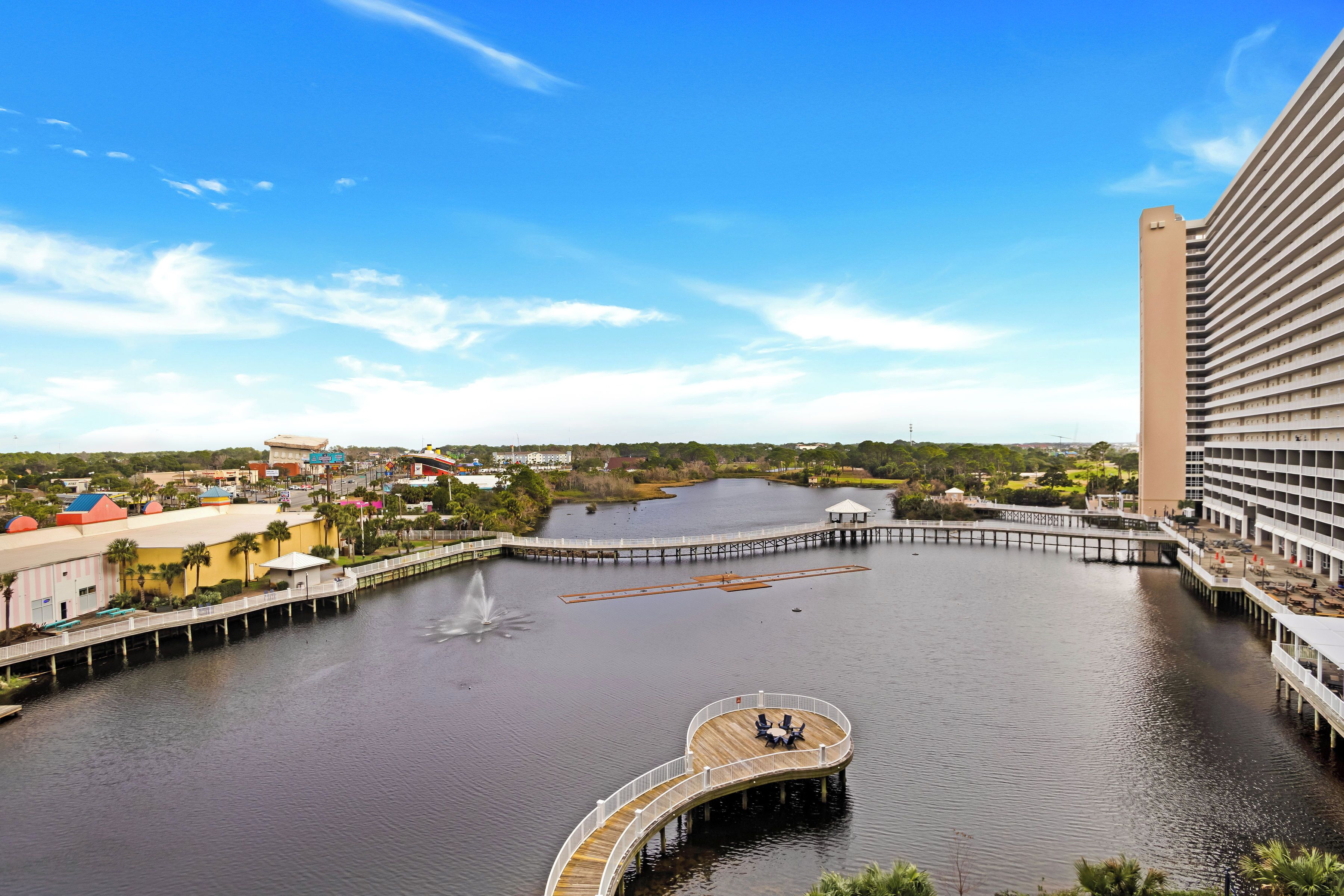 A waterfront hotel with a circular deck, a pier, and a large building with balconies.