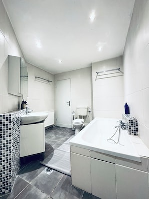 A modern bathroom with a white sink, toilet, and bathtub. - 2BR Apt With Balcony Blumengärten (Vienna)