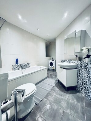 Eenvoudig appartement | Badkamer | Een bad/douchecombinatie, gratis toiletartikelen, een haardroger