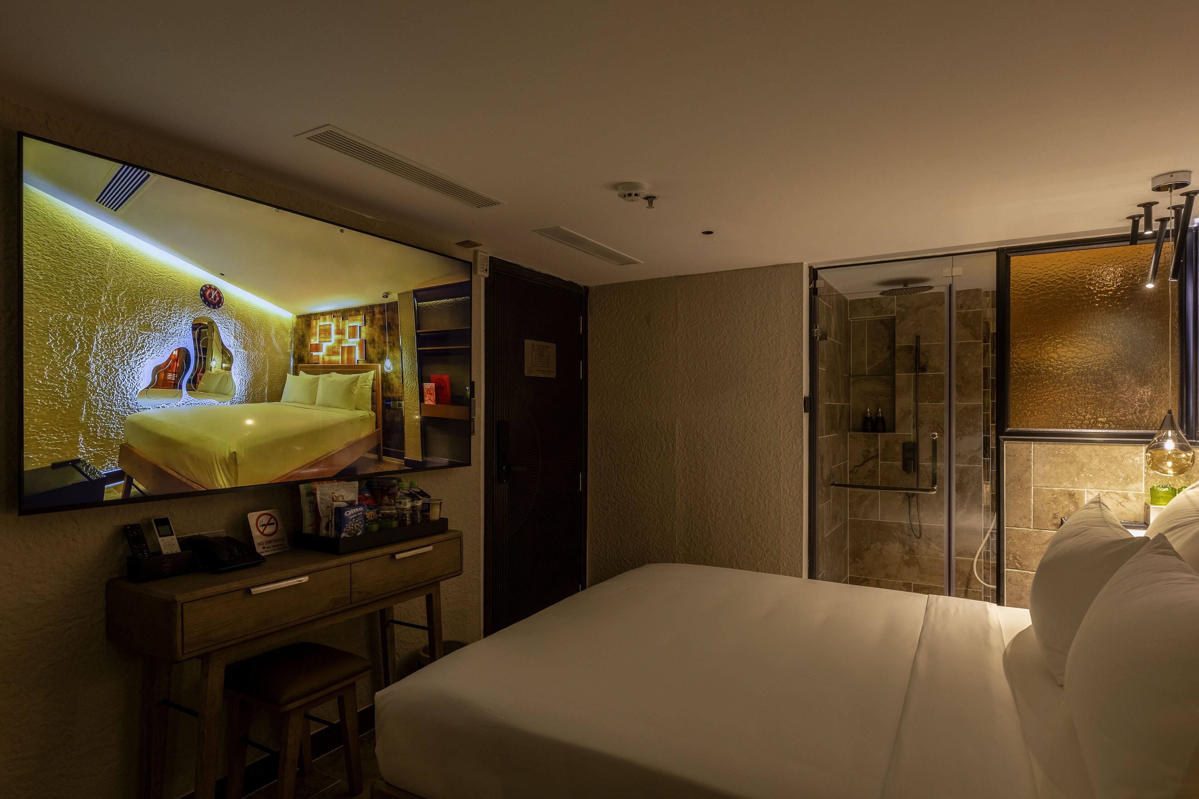 Une chambre d’hôtel avec un grand lit, un bureau avec un téléphone, un miroir et un espace douche.