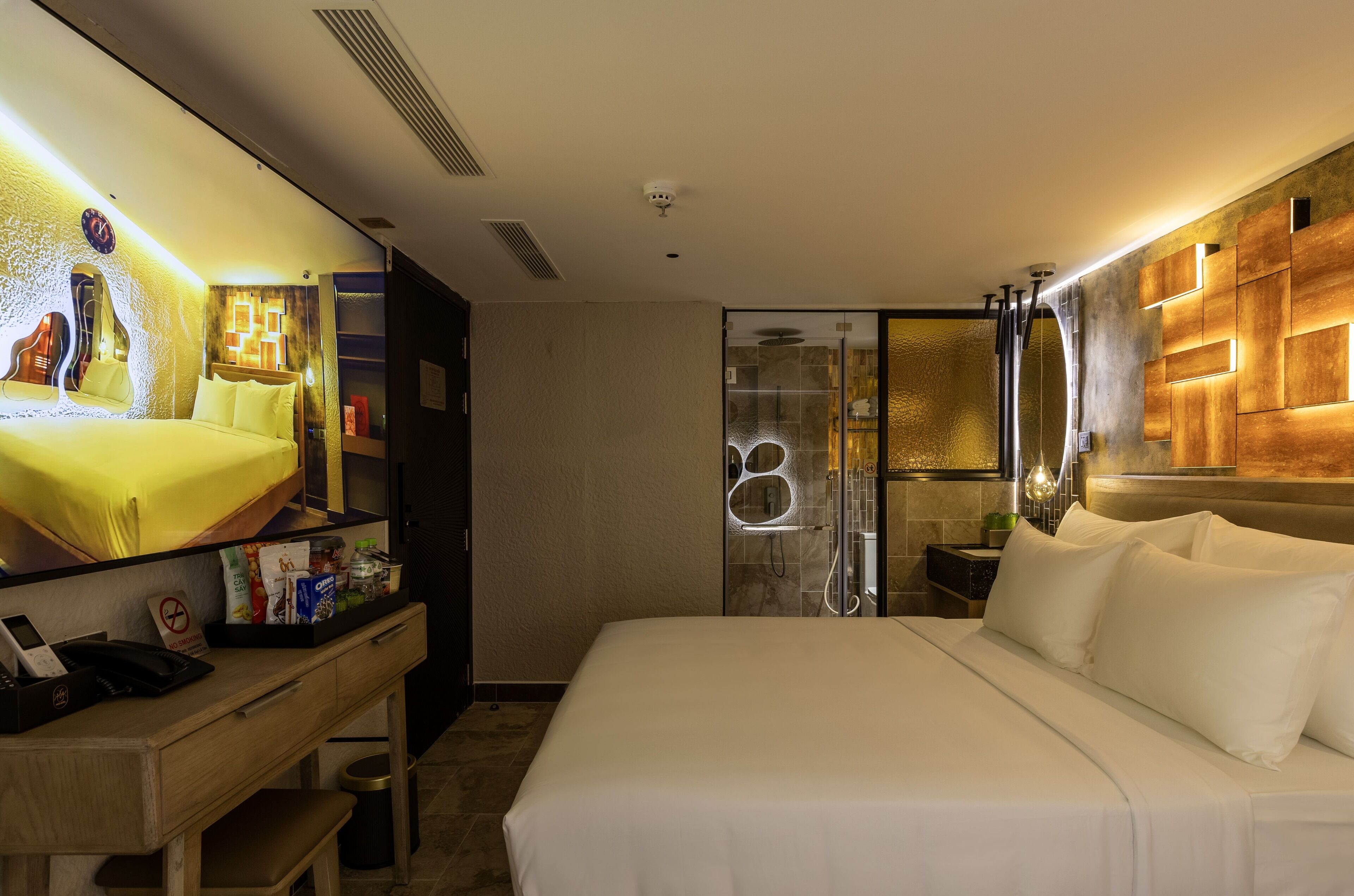 A hotel room with a bed, bedside table, and a large mirror.