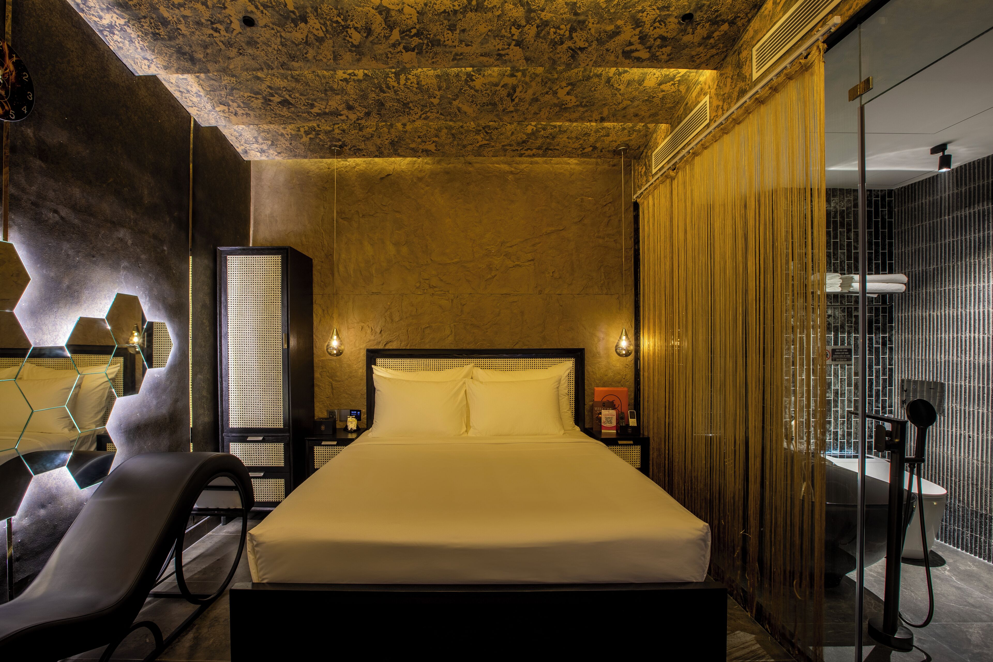 A modern hotel room with a large bed, a seating area, and a shower area.