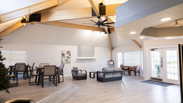 Ein großzügiger Wohnbereich im Loft-Stil mit hohen Decken, freiliegenden Holzbalken und einem großen Deckenventilator.