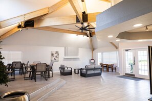 A spacious loft-style living area with high ceilings, exposed wooden beams, and a large ceiling fan. - Disney-Themed 3BR Condo | Pool & Arcade Near Parks (Kissimmee)