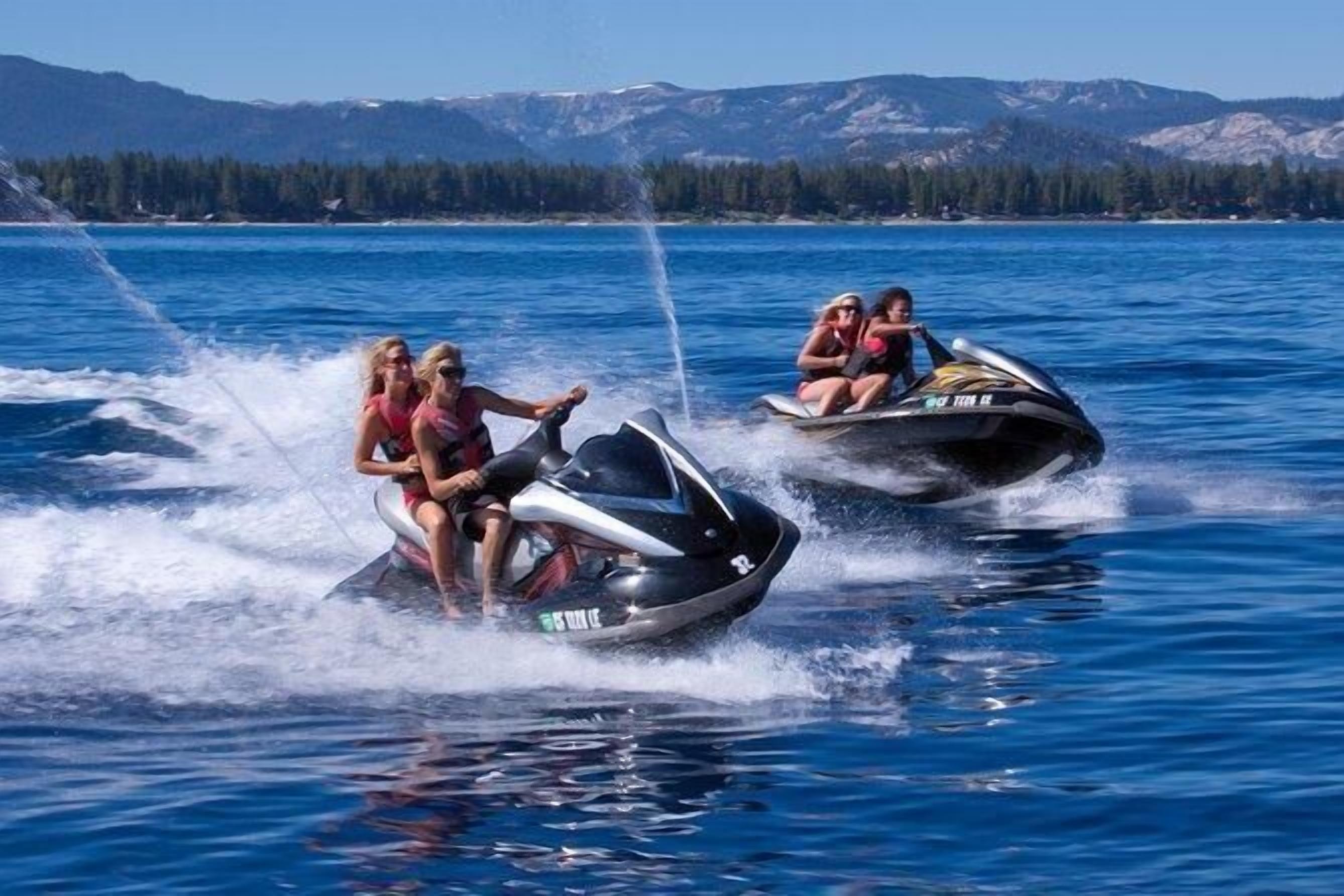 Two jet skis on a lake with mountains in the background.