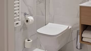 A modern bathroom with a toilet, marble walls, a towel rack, and a toilet paper holder.