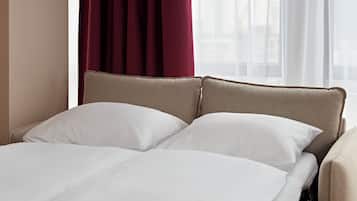 Un letto con testiera, biancheria bianca e una finestra con tende.