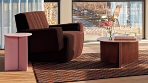 Ein modernes Wohnzimmer mit großem Fenster, einer Couch, einem Couchtisch und einem Beistelltisch.