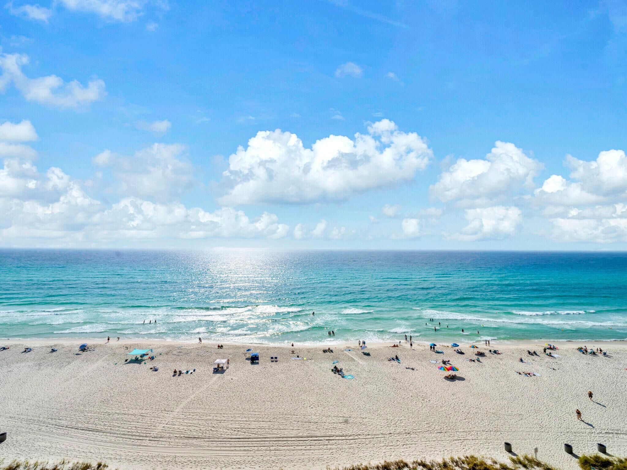 A wide beach with clear skies and calm waters.
