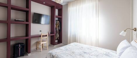 Ett hotellrum med en säng, ett skrivbord, en stol, en tv och en garderob.