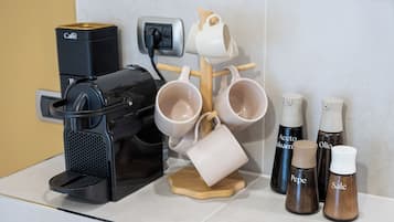 A coffee machine, a mug rack, and two pepper containers on a kitchen counter.