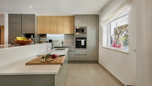 Une cuisine moderne dotée d’un îlot central, d’appareils électroménagers intégrés et d’une grande fenêtre offrant une belle vue.