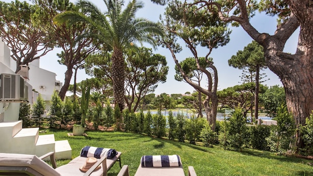 Un espace aménagé au bord de la piscine, avec des chaises longues, un palmier et une vue sur un lac.