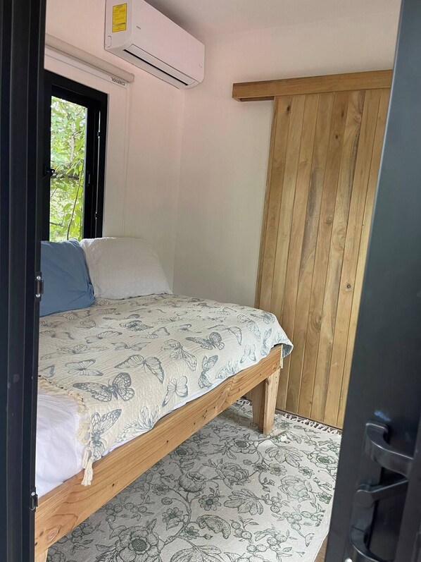 Quarto com cama, guarda-roupa de madeira e ar condicionado.