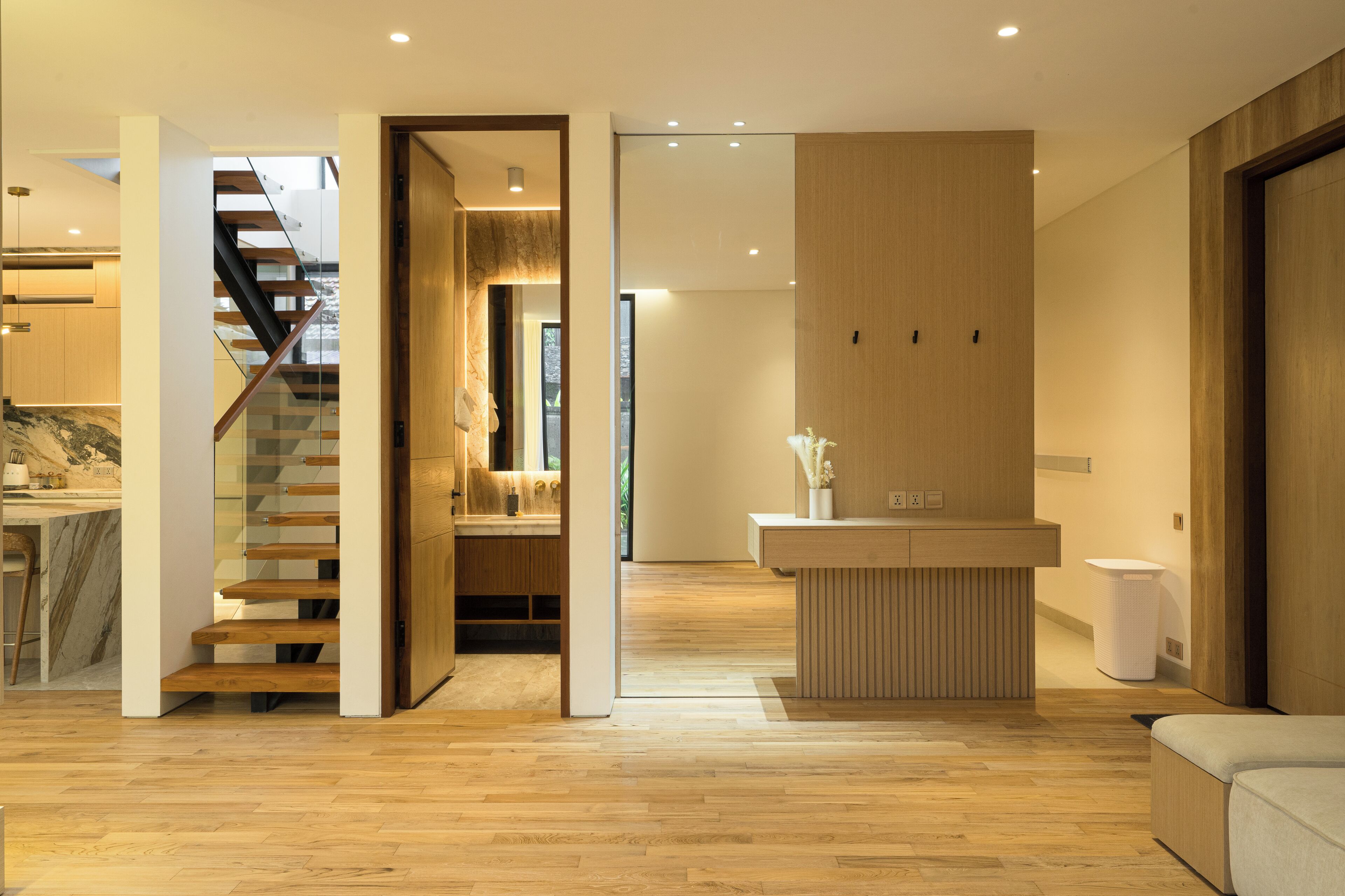 A modern interior with a wooden staircase, a kitchen area, and a reception desk.