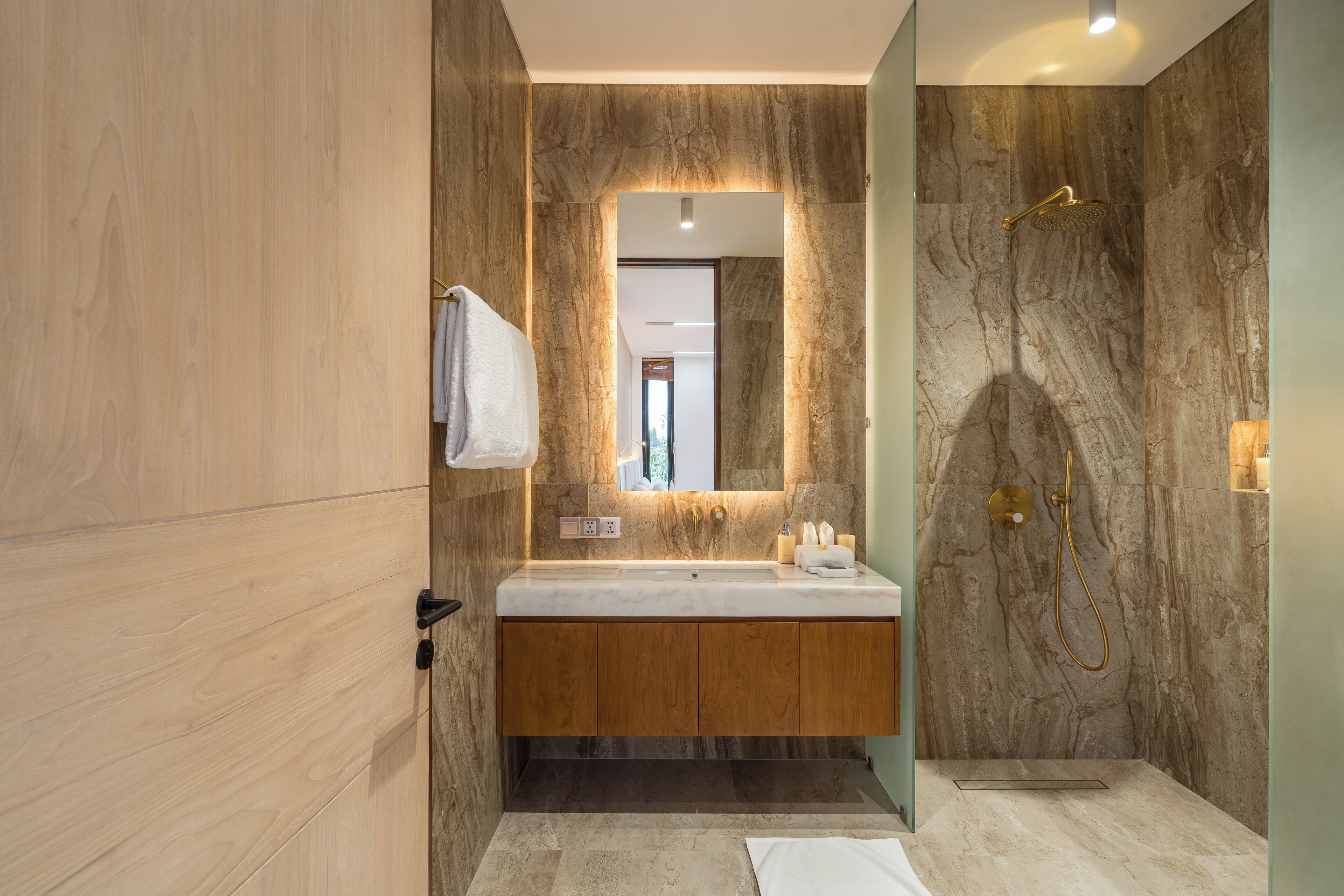 A modern bathroom with a marble vanity, a large mirror, and a shower area.