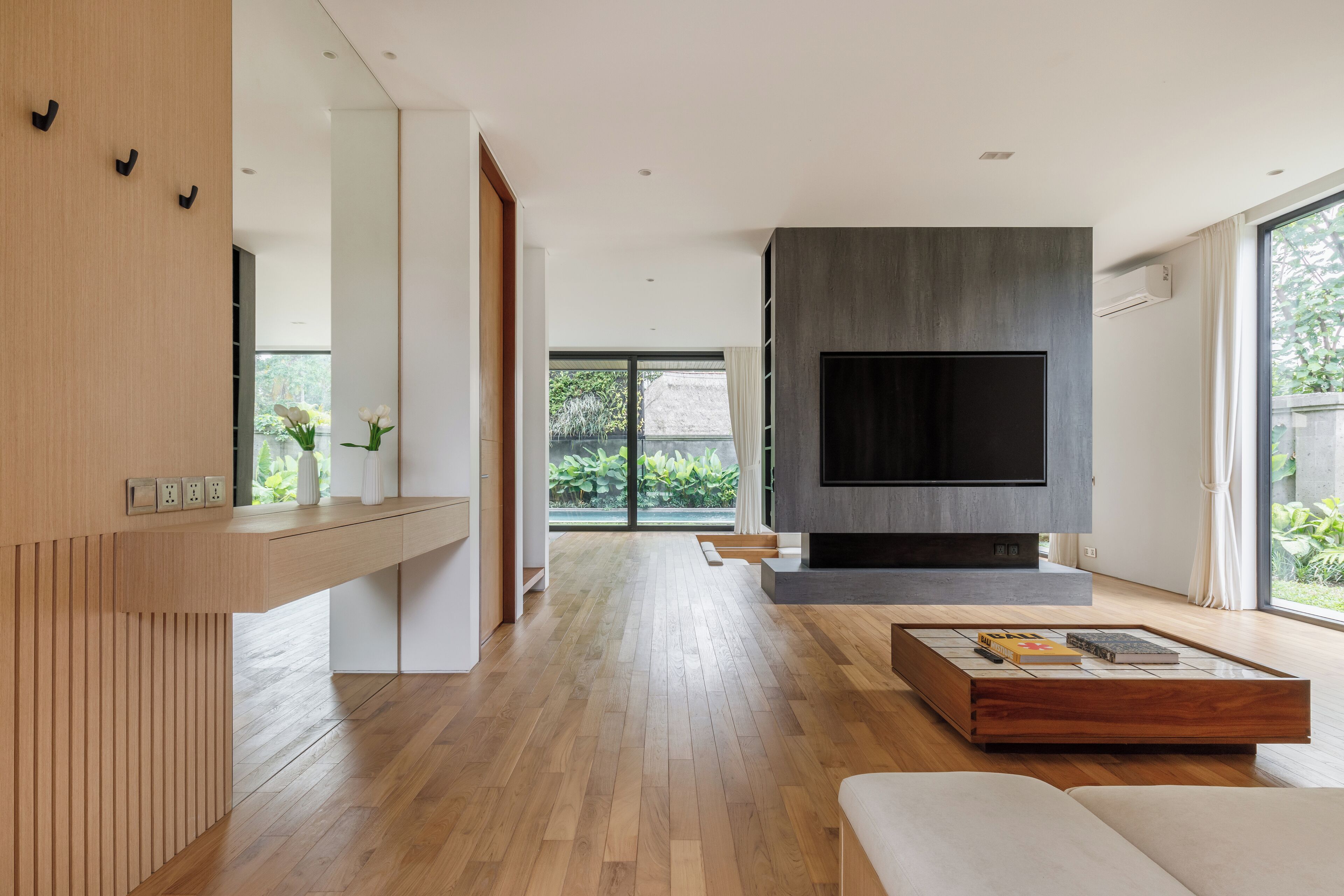 Un salon moderne doté d’un grand téléviseur à écran plat, de planchers en bois et d’un design minimaliste.