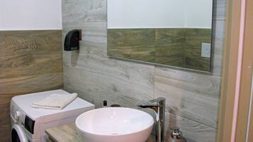 A modern bathroom with a wooden vanity, a white sink, and a mirror.