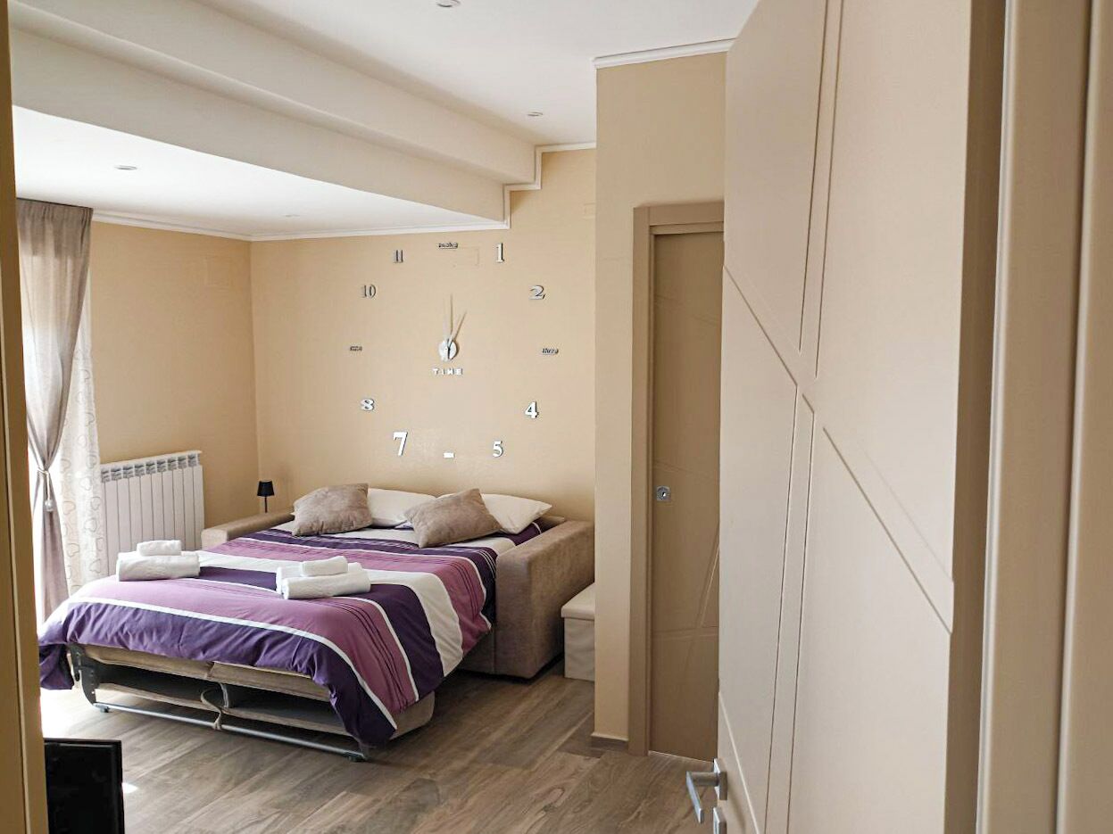 Una camera da letto con un letto, comodini, una sveglia e un termosifone.