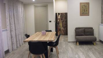 A dining area with a wooden table and chairs, a sofa, and a radiator.