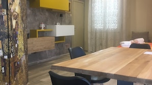 A modern dining area with a wooden table, black chairs, a yellow cabinet, and a decorative wall piece. - Belvedere Vallata Affitti Brevi (Vallata)