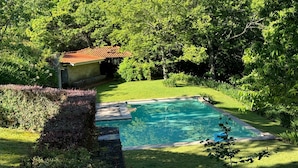 A swimming pool surrounded by lush greenery and a small building with a red roof. - Casa do Alto da Coutada: Mountain View, Private Pool and Wi-Fi (Ponte de Lima)