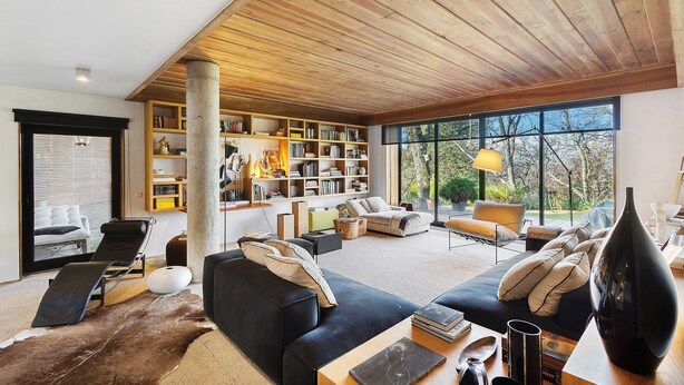 A modern living room with a large bookshelf, a black sofa, a leather chair, and a dining table. - Casa do Alto da Coutada: Mountain View, Private Pool and Wi-Fi (Ponte de Lima)