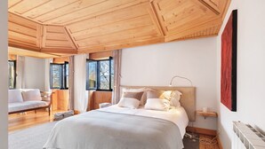 A bedroom with a large bed, wooden ceiling, and a view of the outdoors. - Casa do Alto da Coutada: Mountain View, Private Pool and Wi-Fi (Ponte de Lima)