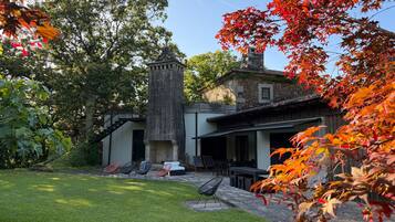 Un bâtiment doté d’une tour en pierre, d’un patio avec des sièges en plein air et d’une pelouse bien entretenue.