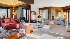 A modern living room with a red armchair, grey sofas, and a wooden coffee table. - Casa do Alto da Coutada: Mountain View, Private Pool and Wi-Fi (Ponte de Lima)