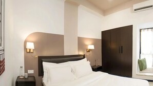 Ein Hotelzimmer mit einem Bett, Nachttischen, Wandlampen, einem Kleiderschrank und einer Klimaanlage.
