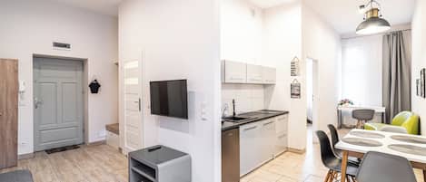 A modern kitchen with white cabinets, a built-in oven, and a dining area with a table and chairs.