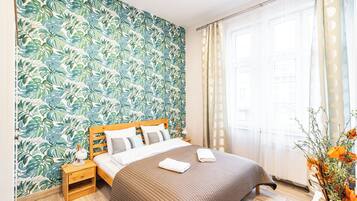 Un dormitorio con cama, mesita de noche y ventana con cortinas.