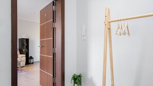 A modern room with a wooden door, a black bench, a small plant, and a hanging clothes rack. - Sliema Seaside Penthouse with Terrace (Sliema)