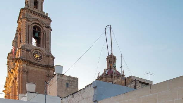 A patio with a table and chairs, a bell tower in the background, and a view into a living area. - Sliema Seaside Penthouse with Terrace (Sliema)