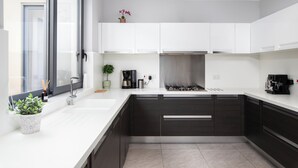 A modern kitchen with white countertops, dark cabinetry, a built-in stove, and a window with a view. - Sliema Seaside Penthouse with Terrace (Sliema)