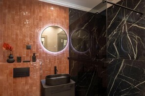 A modern bathroom with a round mirror, a sink, and a shower area. - Pervicacia Lux Studios (Dubrovnik)