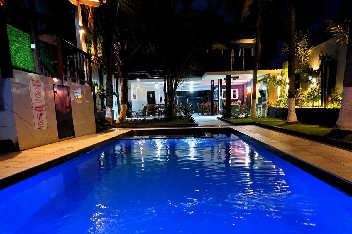 A swimming pool with a clear view of the surrounding buildings and a well-lit pathway.