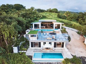 Ein modernes Haus mit Swimmingpool, Sitzgelegenheiten im Freien und üppiger Bepflanzung.